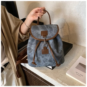 Detail of vintage canvas backpack with leather trim and drawstring closure in use