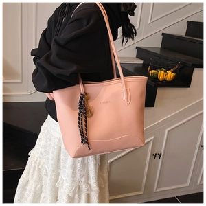 Detail of pink lychee grain leather tote bag with FASHION logo and striped ribbon
