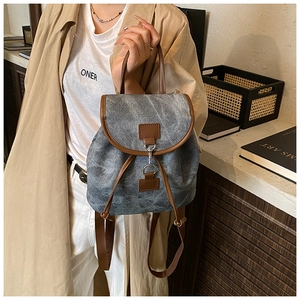 Detail of vintage denim backpack with brown leather trim and metal hook closure