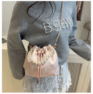 Detailed view of pink jacquard satin bucket bag with pearl handle and floral embroidery