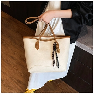 Detail of cream white tote bag with lychee grain texture and brown leather trim