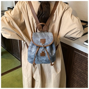 Detailed back view of a grey canvas backpack with brown leather straps on a model