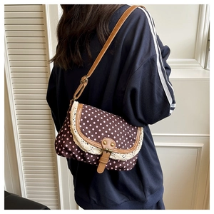 Dettaglio borsa vintage a pois con bordo in pizzo e tracolla in finta pelle con fibbia