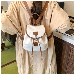 Detail view of mini canvas backpack featuring brown leather trim and metal buckle closure