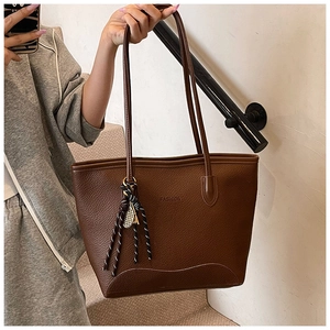Detail of dark brown tote bag featuring pebbled leather texture and fashion embossing