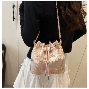 Detail of pink floral jacquard bucket bag with large pearl handle and metal chain strap