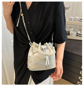 Detail van de geborduurde bloemen emmer tas met parel handvat en metalen ketting