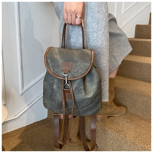 Detail of retro canvas backpack with brown faux leather trim and metallic buckle closure