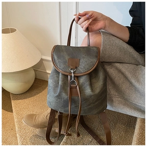 Detail of vintage canvas backpack featuring drawstring closure and premium leather accents