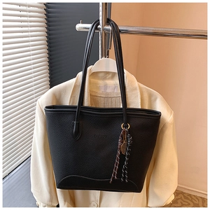Close-up of black lychee grain tote bag with FASHION logo and tennis racket charm