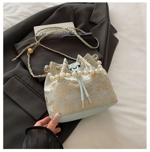Detail of the blue jacquard bucket bag showing pearl handle and gold hollow charm