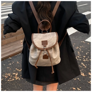 Detail of retro canvas backpack with drawstring and brown straps in outdoor setting