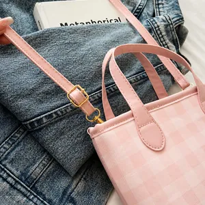 Dettagli di una borsa a quadretti rosa con fibbia dorata regolabile e chiusura a moschettone