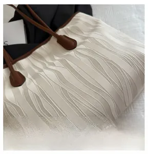 Detail of beige tote bag with unique wave texture and contrast brown leather handles