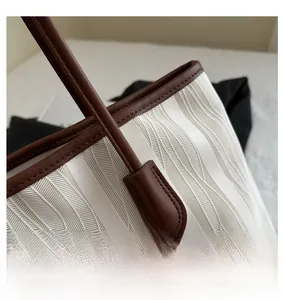 Detail of white wavy texture fabric and brown leather stitching on a tote bag