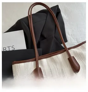 Close-up of the beige tote bag with wavy texture and durable brown shoulder straps