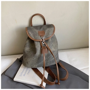 Detailed view of the dark grey matte canvas backpack with brown leather trim and metal hook