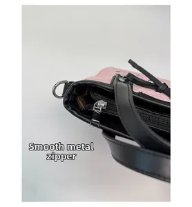 Gros plan sur la fermeture éclair argentée et le cuir rose texturé du sac seau