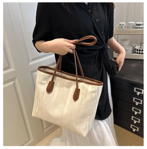 Detail of wavy jacquard canvas texture on a beige tote bag with dark brown leather straps