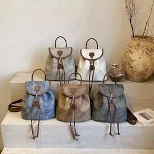 Vintage matte leather backpacks in five colors displayed on minimalist stone steps
