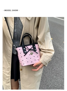 Sac seau rose plissé avec nœuds noirs et pendentif en forme de cœur porté en extérieur