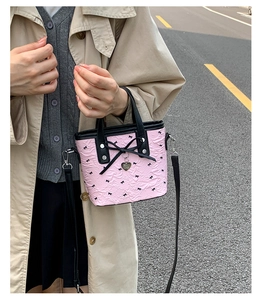 Vue détaillée du sac rose plissé orné de nœuds noirs et d'un pendentif en forme de cœur