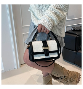 Close-up of black and white leather handbag featuring geometric embossed patterns and gold buckle