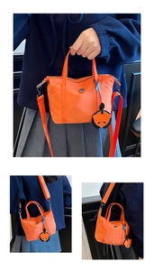 Détail du sac dumpling en nylon orange vif avec bandoulière réglable et breloque de panda