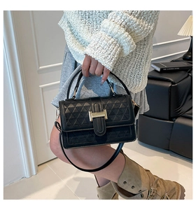 Detail of black geometric textured handbag with metal buckle and scarf on top handle