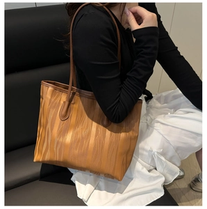 Detail of a brown tote bag with wavy texture on a leather sofa with 80-100 characters