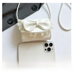 Comparación detallada del mini bolso blanco con lazo y smartphone para ver el tamaño