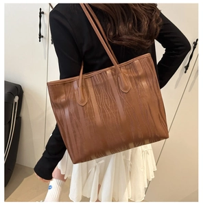 Detail of brown tote bag with vertical wood grain texture and slim shoulder straps