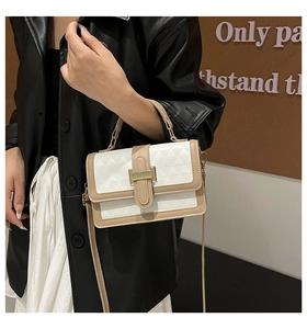 Detail of white textured crossbody bag with camel trim and gold buckle on a model