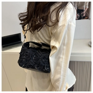 Vue détaillée du sac noir à pétales de roses 3D porté par un mannequin en scène