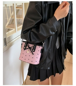 Détail du sac bandoulière rose avec motifs de nœuds noirs et pendentif en cœur