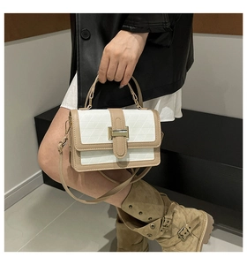 Detail of a quilted crossbody bag with color-block design and golden metal clasp lock