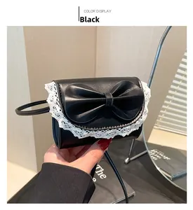 Detalle del mini bolso bandolera negro con lazo grande y ribete de encaje blanco