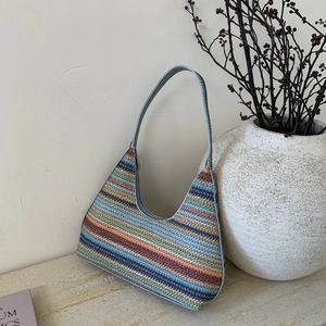 Colorful striped woven shoulder bag with blue leather trim on marble surface