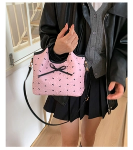 Sac bandoulière rose à motifs nœuds noirs porté par un mannequin pour style quotidien