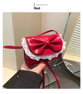Detalle de un mini bolso rojo con un lazo grande y adornos de encaje blanco fino