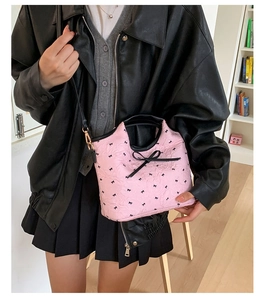 Détail du sac seau rose avec imprimé nœuds noirs et garniture en cuir sur un mannequin