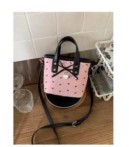 Détail du sac seau rose à motifs nœuds avec pendentif cœur et poignée en cuir