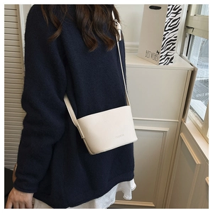 Detail of cream lychee texture crossbody bag with embossed Fashion lettering