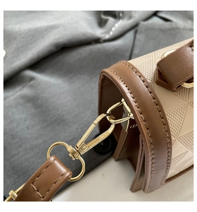 Detailed close-up of quilted beige handbag featuring gold metal hardware and brown strap