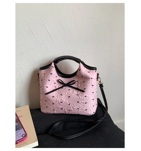 Détail du sac à main matelassé rose avec nœud noir et bandoulières contrastées