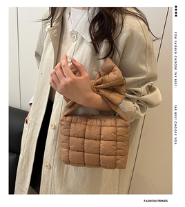 Detail of caramel brown quilted puffer handbag featuring a stylish oversized bow accent