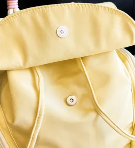 Dettaglio della chiusura magnetica argento su uno zaino in nylon giallo