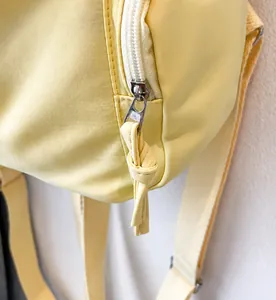 Dettaglio della cerniera scorrevole e delle cuciture su uno zaino in nylon giallo