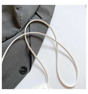 Détail d'un mini sac bandoulière blanc avec bordure en dentelle et fine lanière en cuir