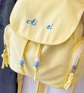 Dettaglio dello zaino in nylon giallo chiaro con ricamo Ai Mei e perline colorate